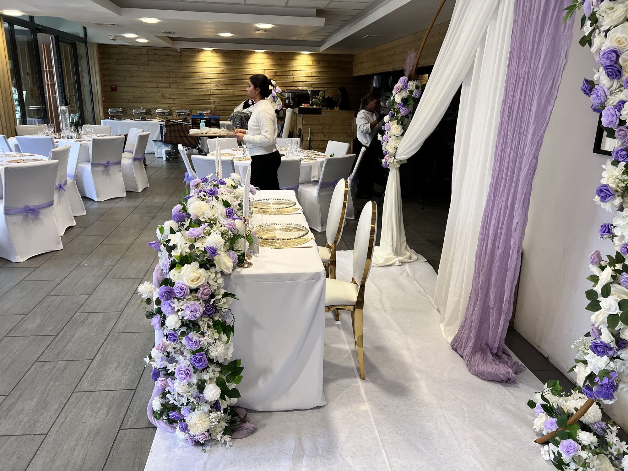 Salle du Pavillon à Épône dressée pour 70 convives : coin des mariés fleuri et tables rondes lilas et doré