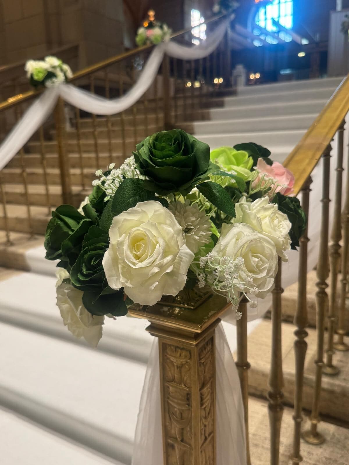 Escalier d'honneur drapé de blanc, rampe de bronze et bouquets de roses blanches et vertes, Montréal